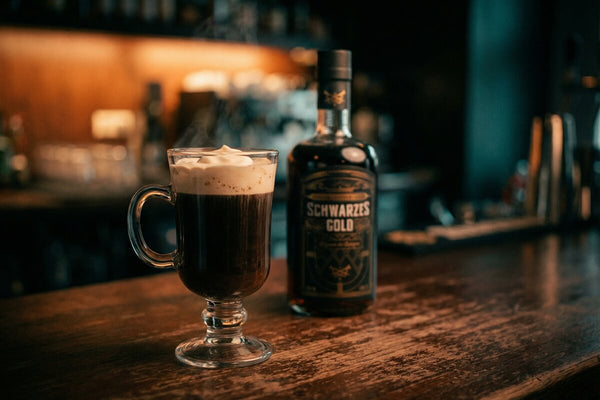 Irish Coffee mit Schwarzes Gold Kaffeelikör im Glasbecher mit Sahnehaube und aufsteigendem Dampf