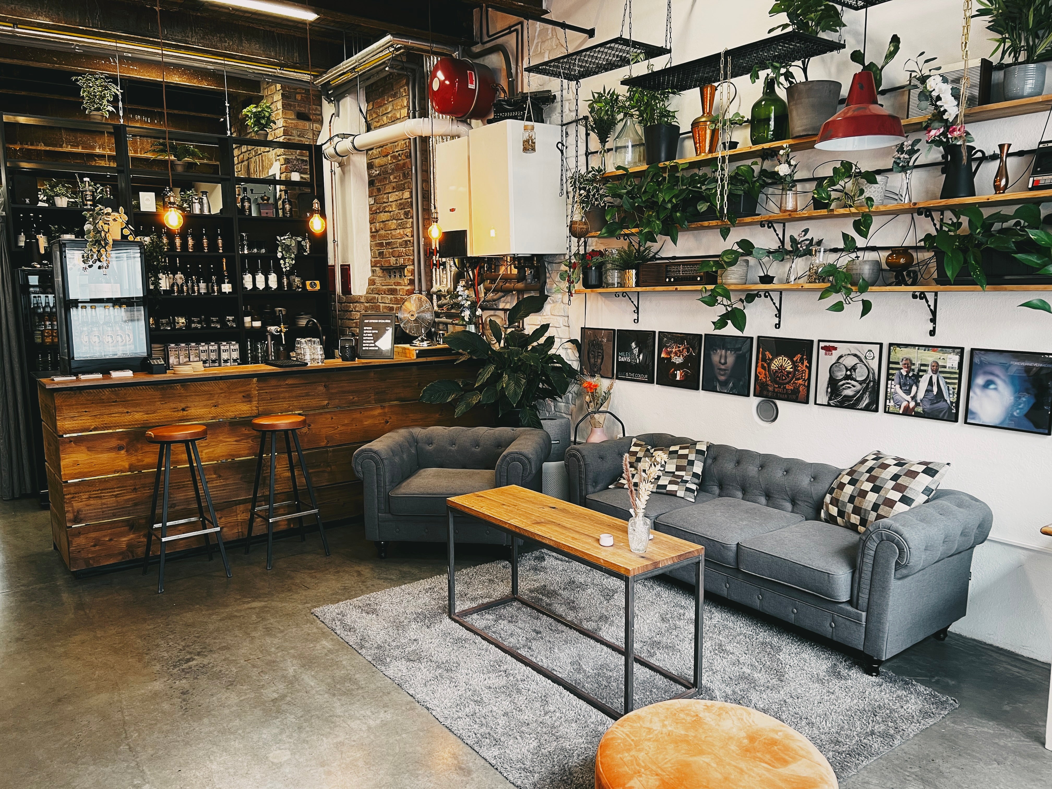 Gemütliche Lounge-Ecke mit Espressobar, stilvollen Pflanzen und Vinyl-Wanddekoration bei as/if spaces in Köln Nippes. Perfekt für kreative Meetings, Seminare und Events in entspannter Atmosphäre.