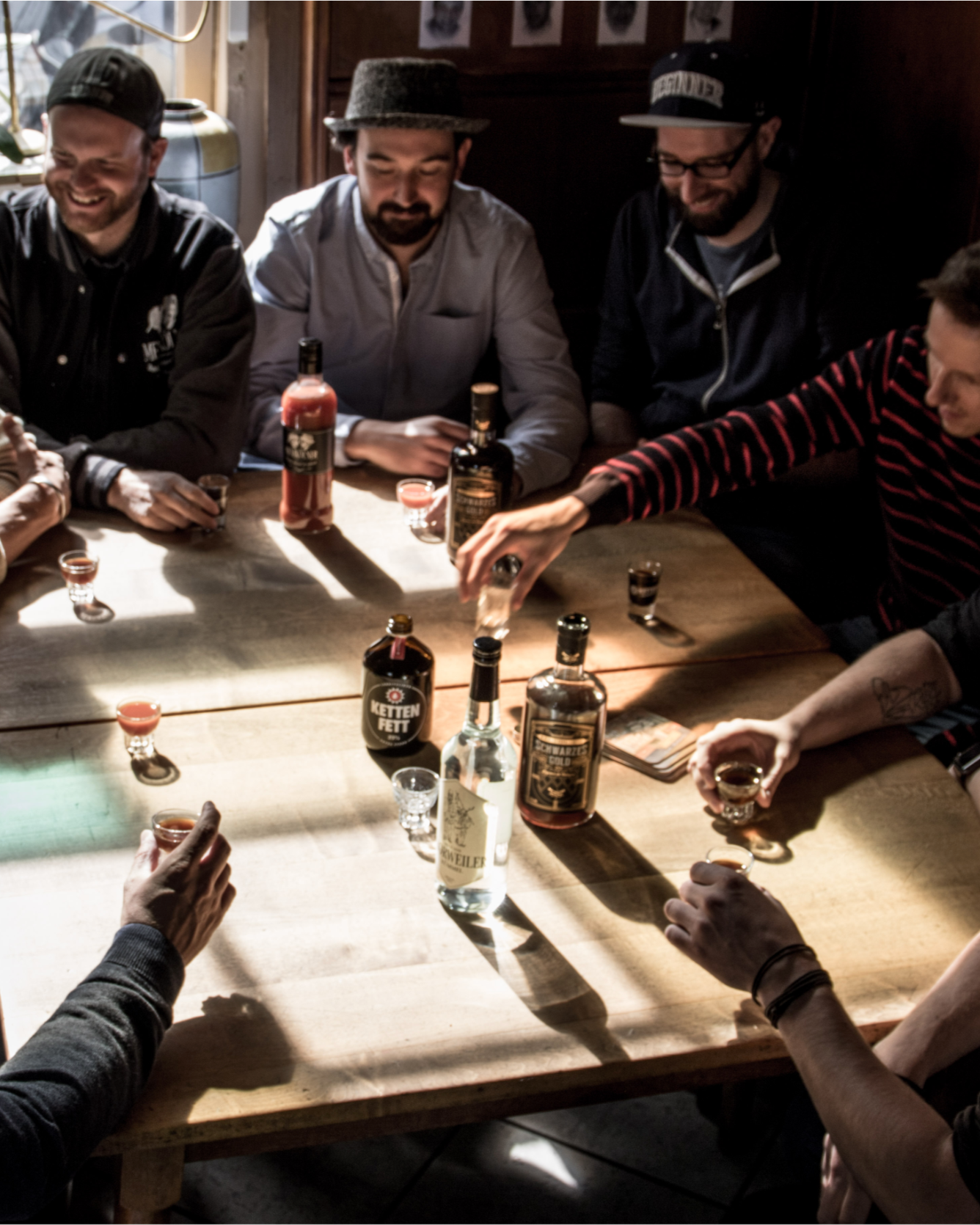 Erwachsene Gäste sitzen mit Kölner Spirituosen an einem Tisch