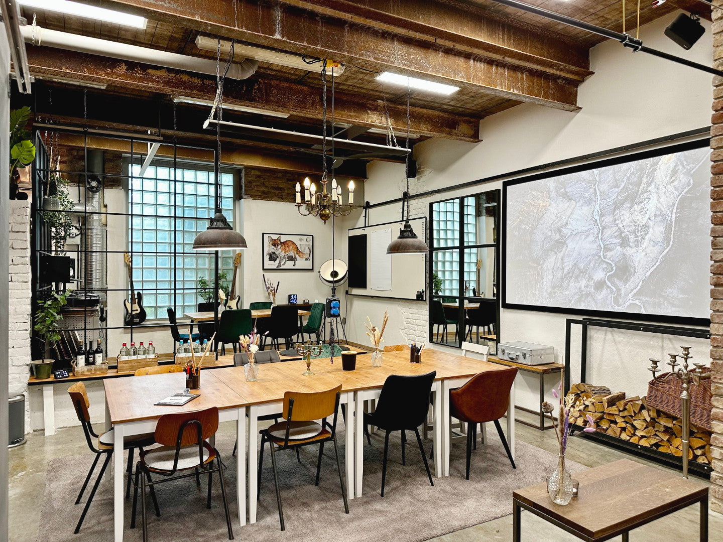 Industriell gestalteter Seminarraum von as/if spaces in Köln Nippes mit Holztisch, modernen Lampen und großer Leinwand. Ideal für kreative Meetings, Seminare und Workshops in einzigartiger Atmosphäre.
