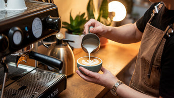 Barista gießt Latte Art an der Siebträgermaschine von as.if.spaces.