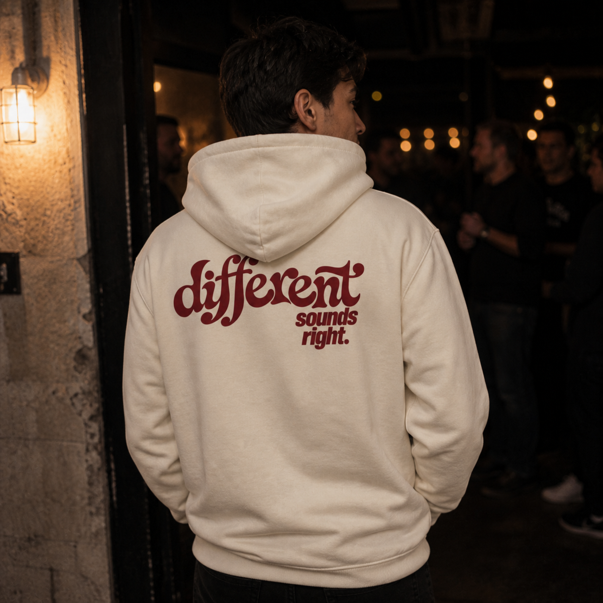 Different Sounds Right Bio-Hoodie in Natural Raw - Lifestyle-Rückenansicht vor einem Musikvenue - as.if.threads#Farbe_Natural Raw