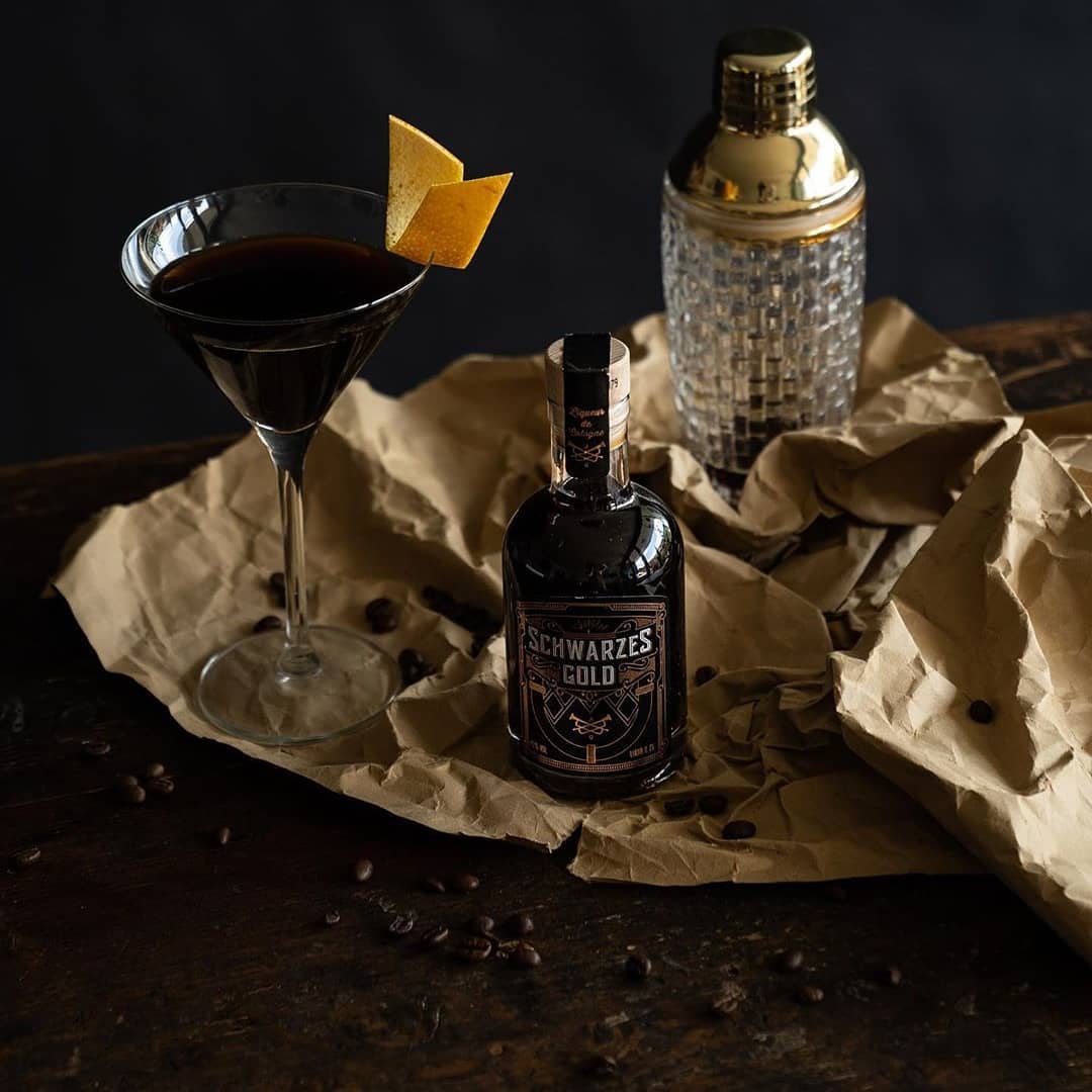 Schwarzes Gold neben dunklem Cocktail und silbernem Shaker